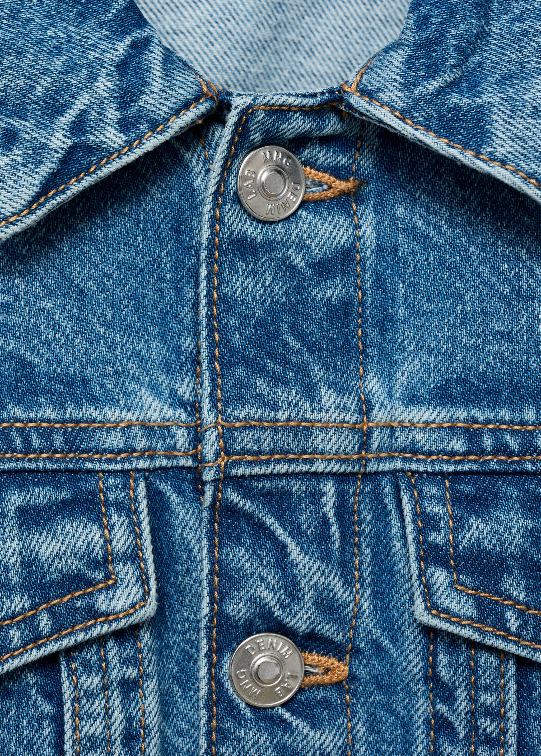 Close-up of a blue denim jacket featuring contrast topstitching and metallic buttons.