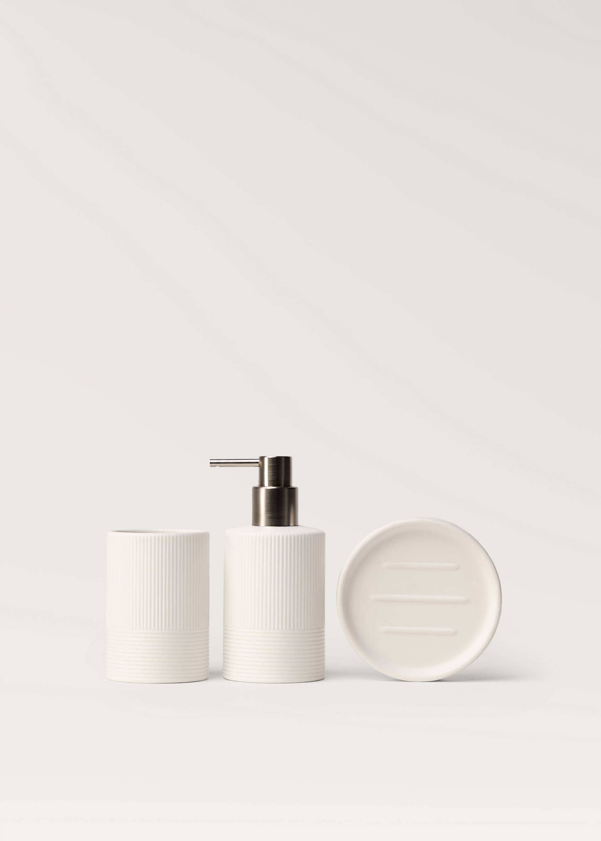 Off-white ceramic soap dish with horizontal ridges, part of a bathroom set.