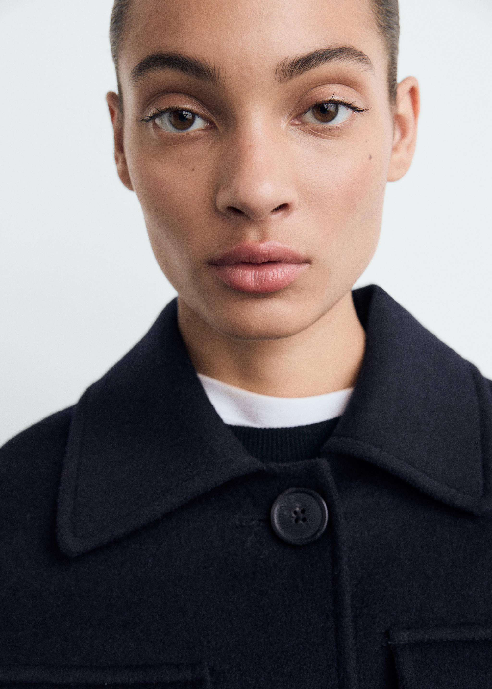 Close-up of a dark navy blue collared jacket with a button closure.