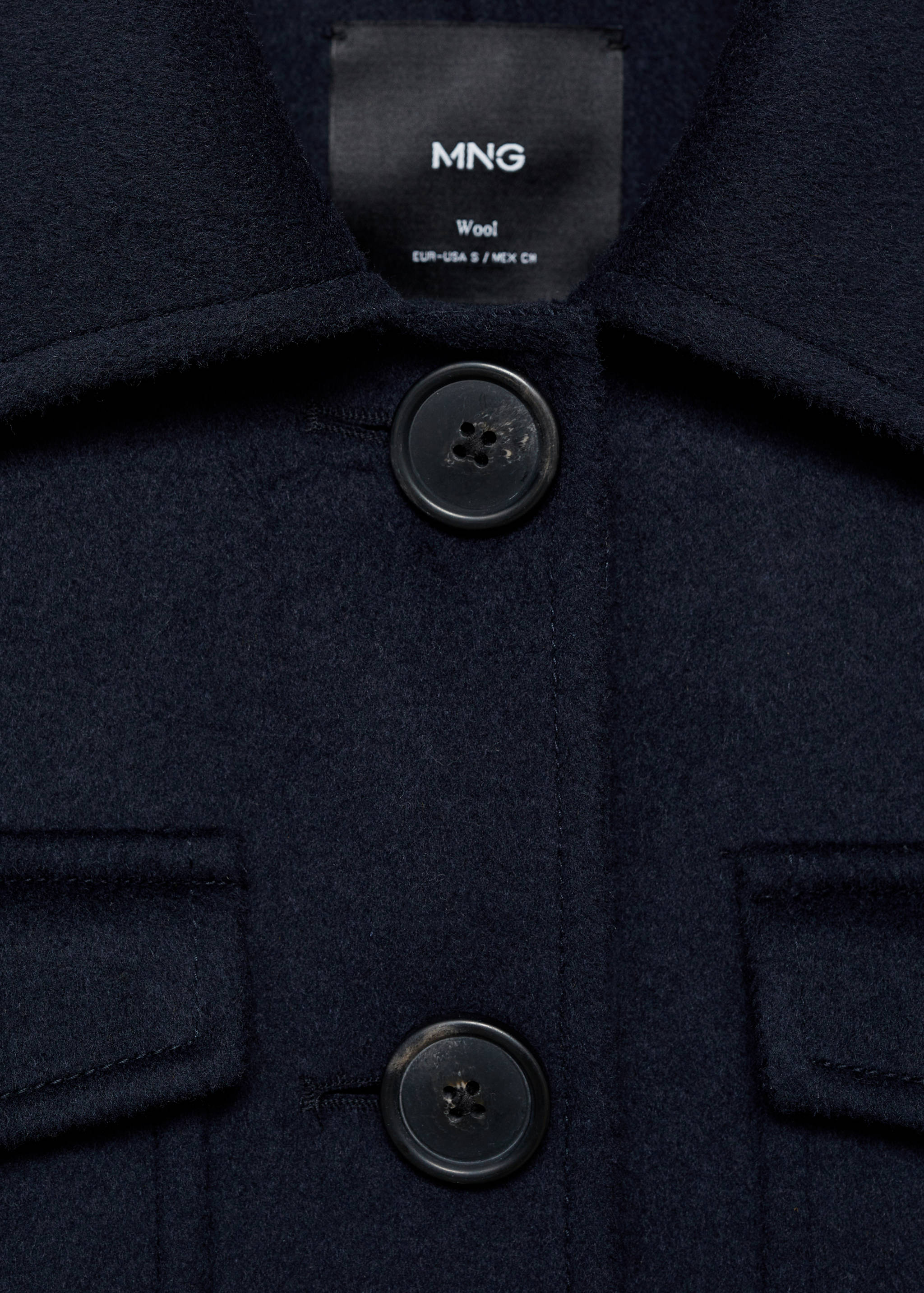 Dark navy wool jacket detail showing the collar, buttons, and chest pockets.