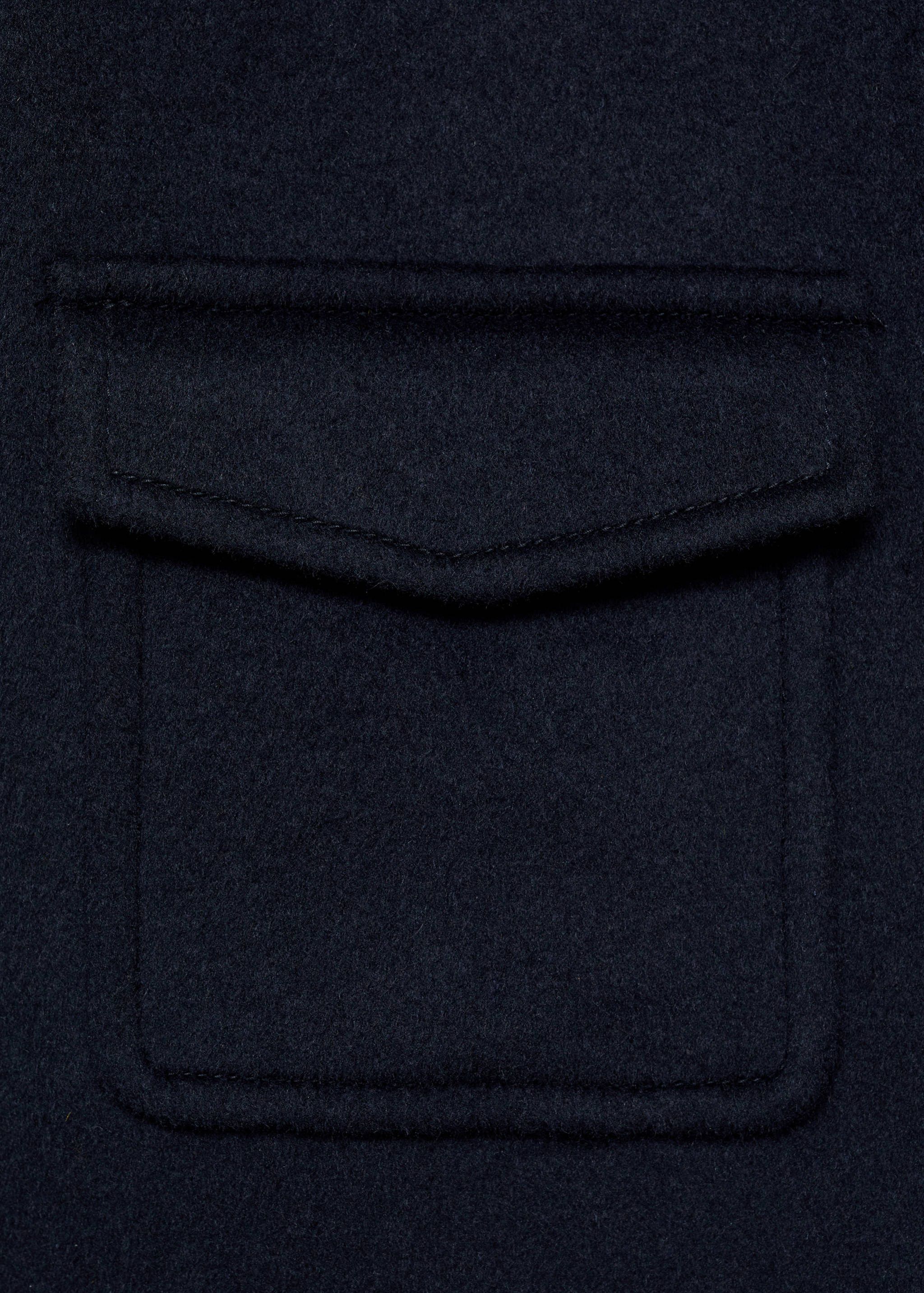 Close-up of navy jacket fabric and patch pocket detail.