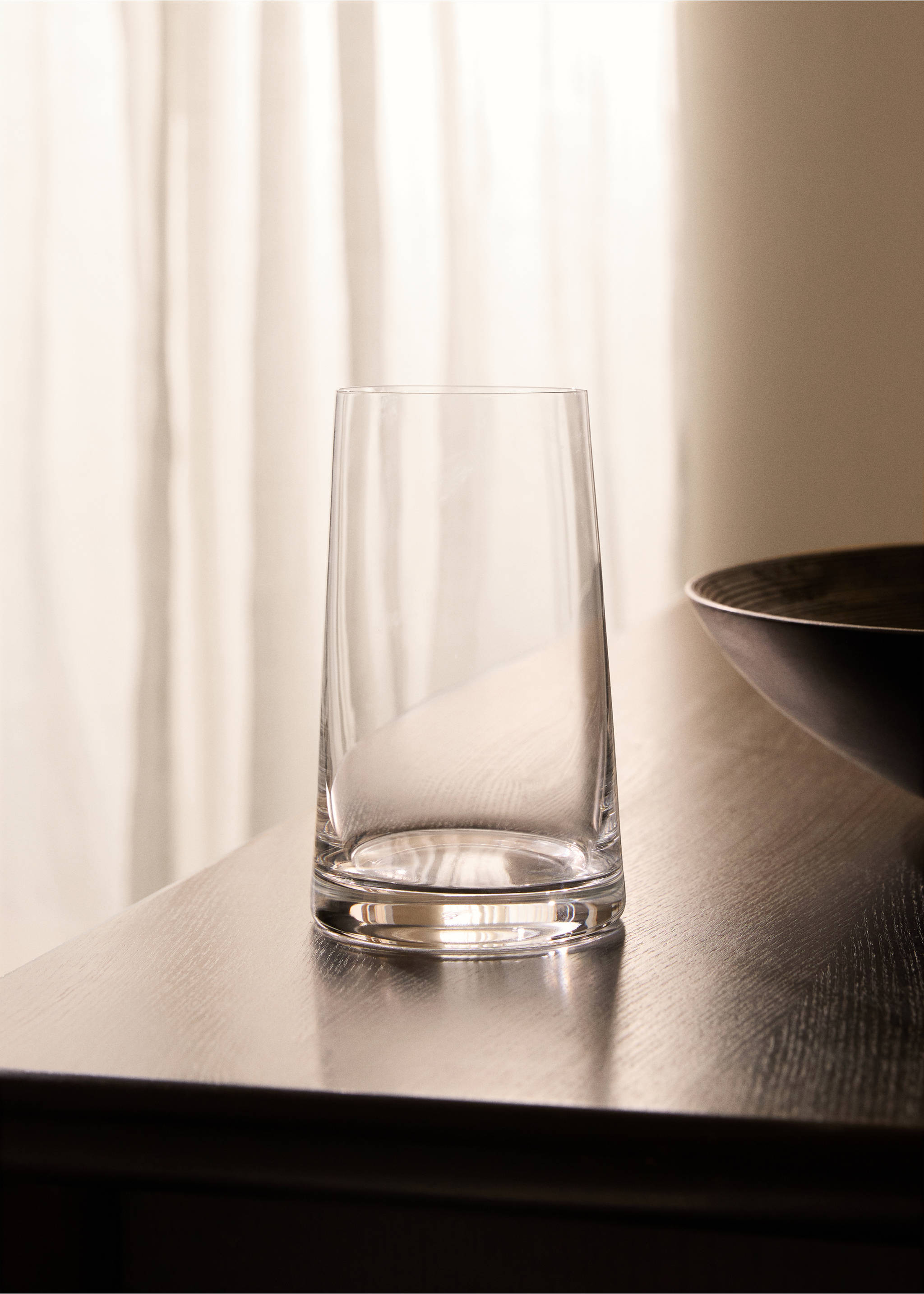 Clear glass vase with a thick base on a wooden surface., Ice Grey. Ref: 87062927-00.