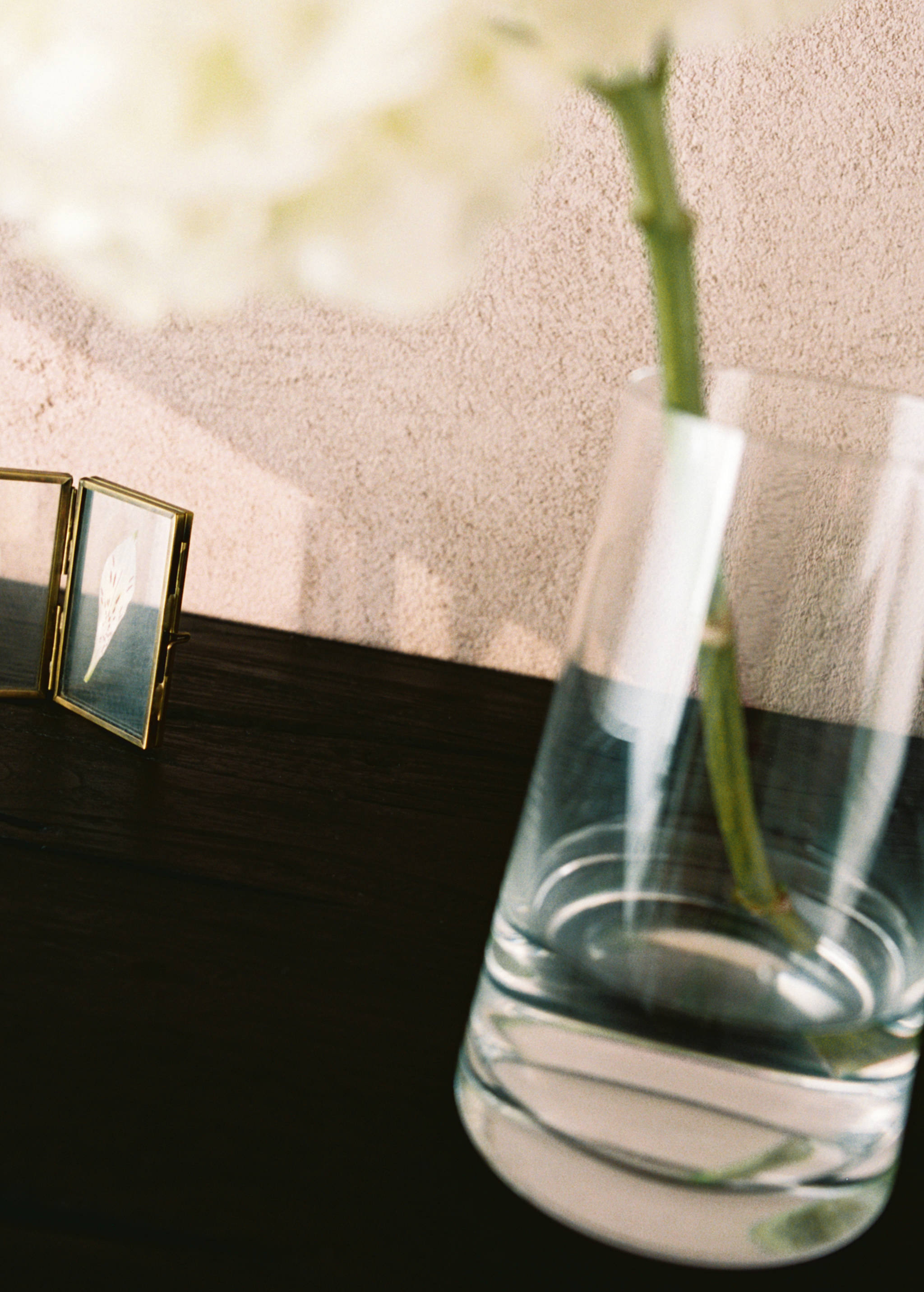 Clear conical glass vase holding a single flower on a dark surface.