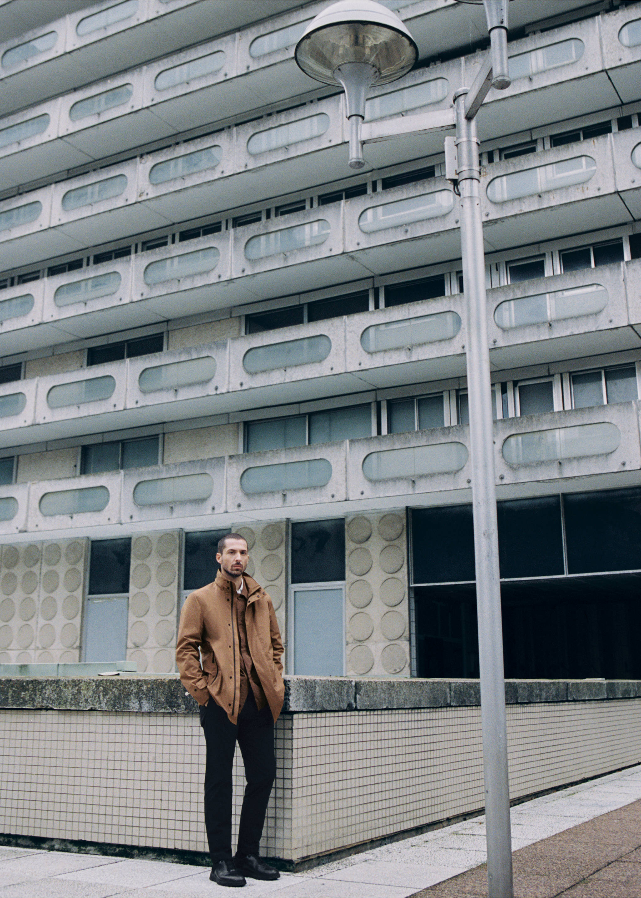 Dark trousers worn by a man standing outdoors against a concrete building., Black. Ref: 87064389-00.