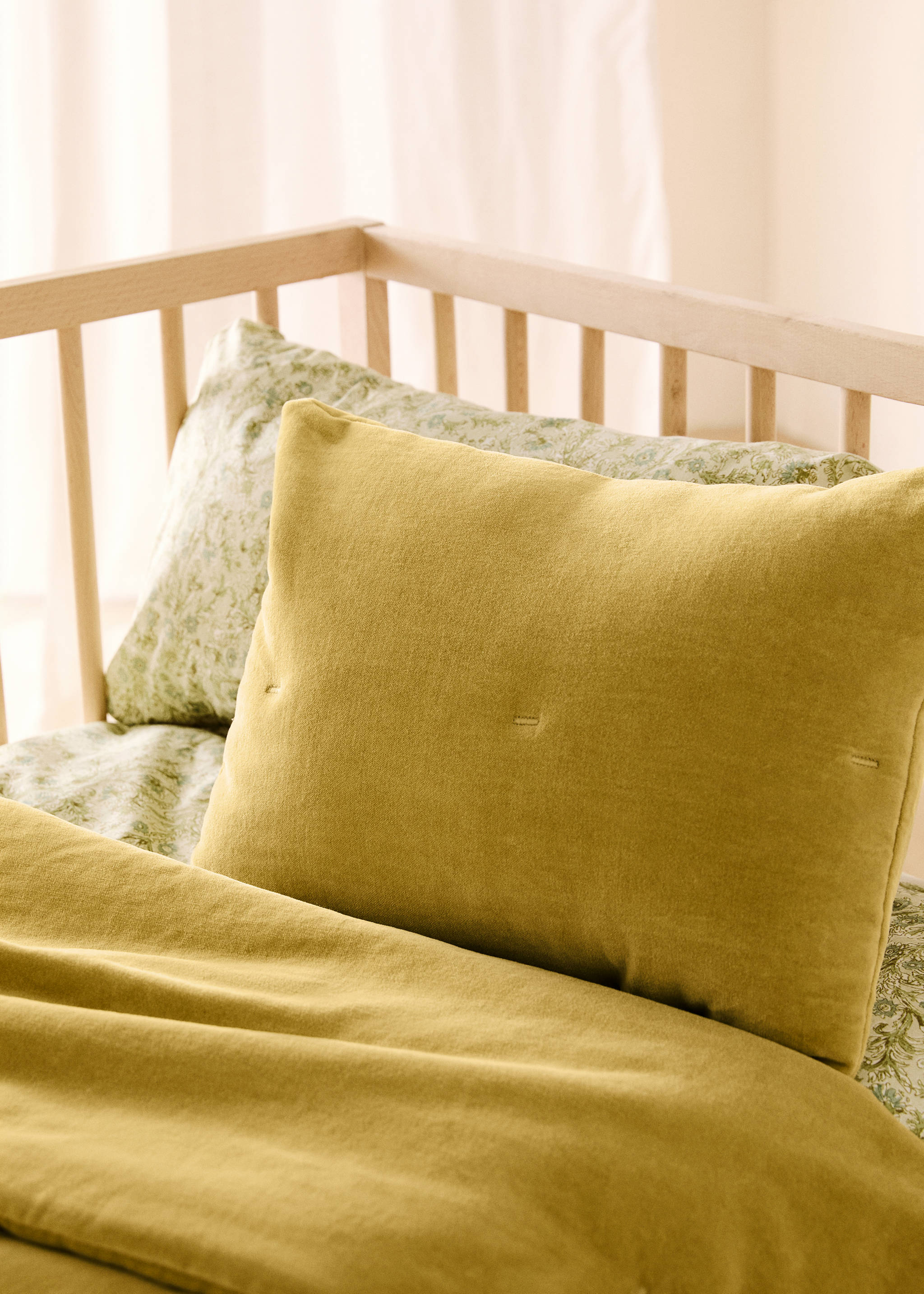 Mustard-yellow cushion cover with stitching details on a bed.