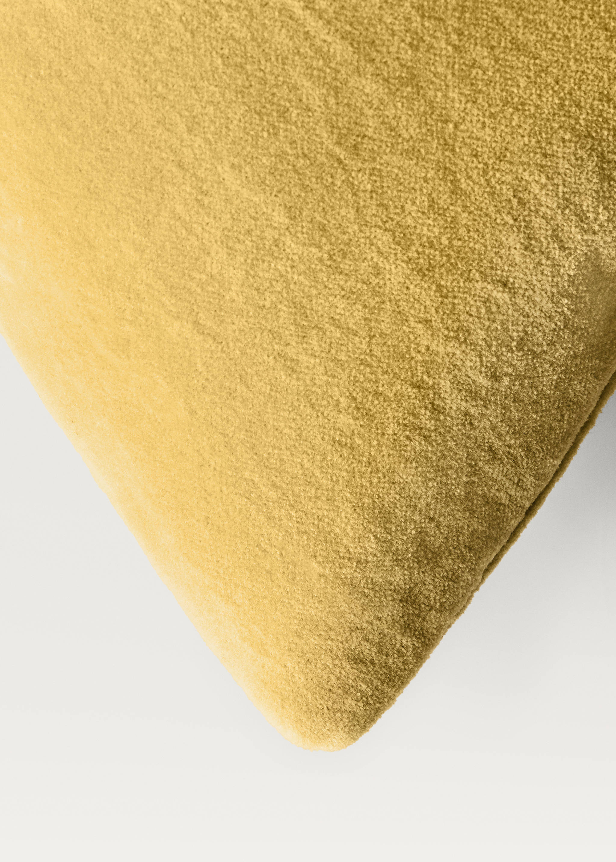 Close-up of a yellow velvet cushion cover corner.