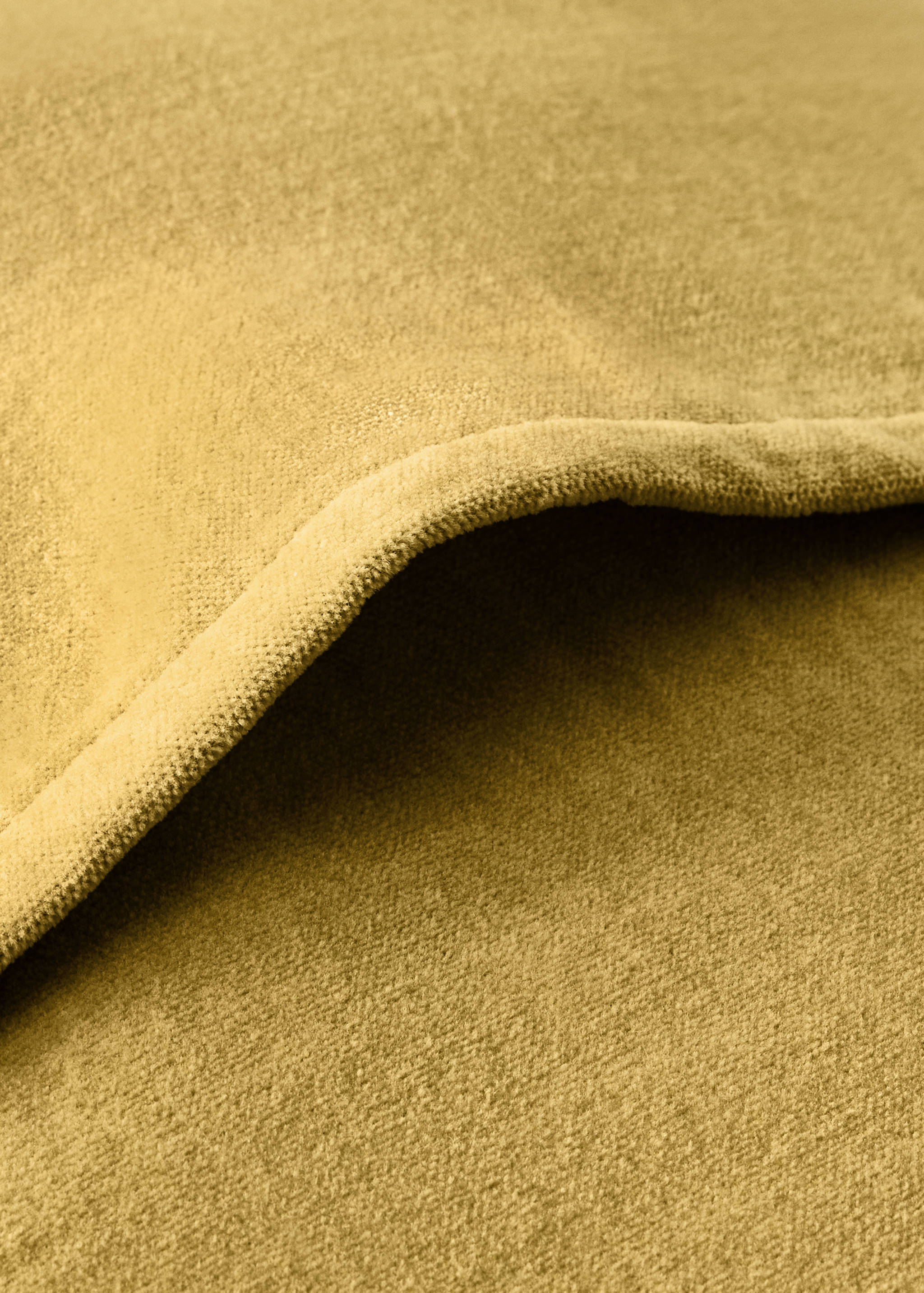 Close-up of a mustard yellow bed cushion cover in a textured fabric.