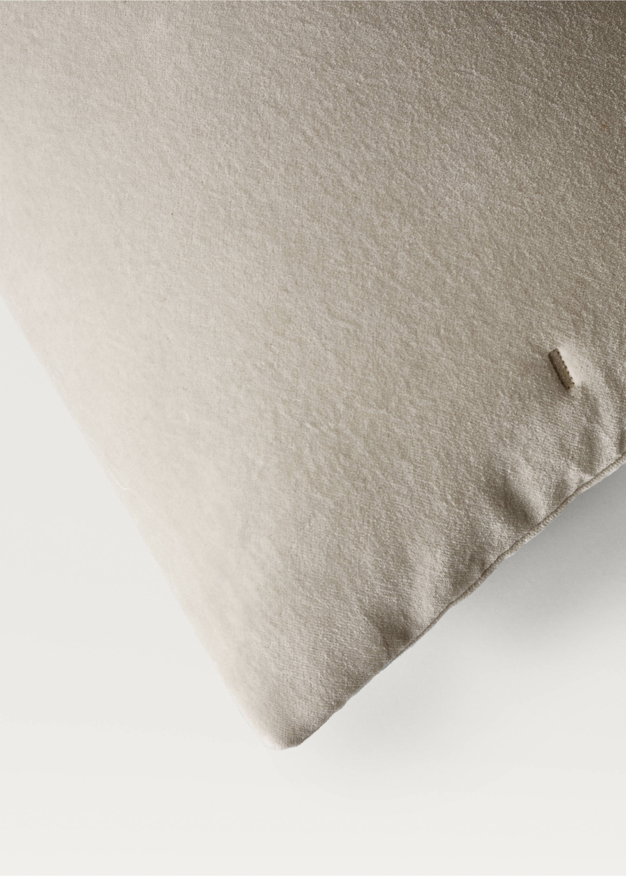 Close-up of a textured beige cushion cover with a small label., Light/Pastel Grey. Ref: 87065144-00.