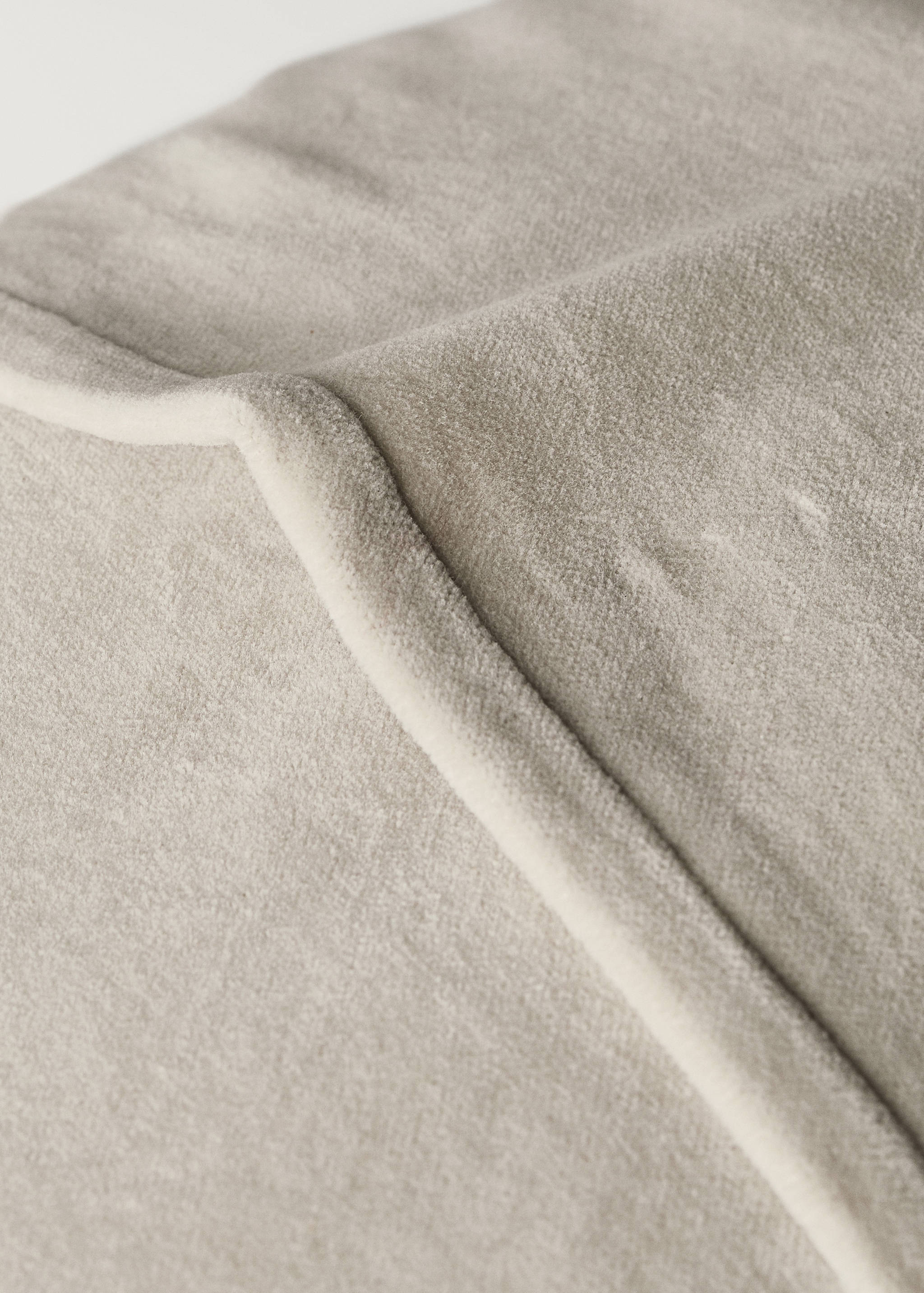 Close-up of a soft beige velvet cushion cover texture.