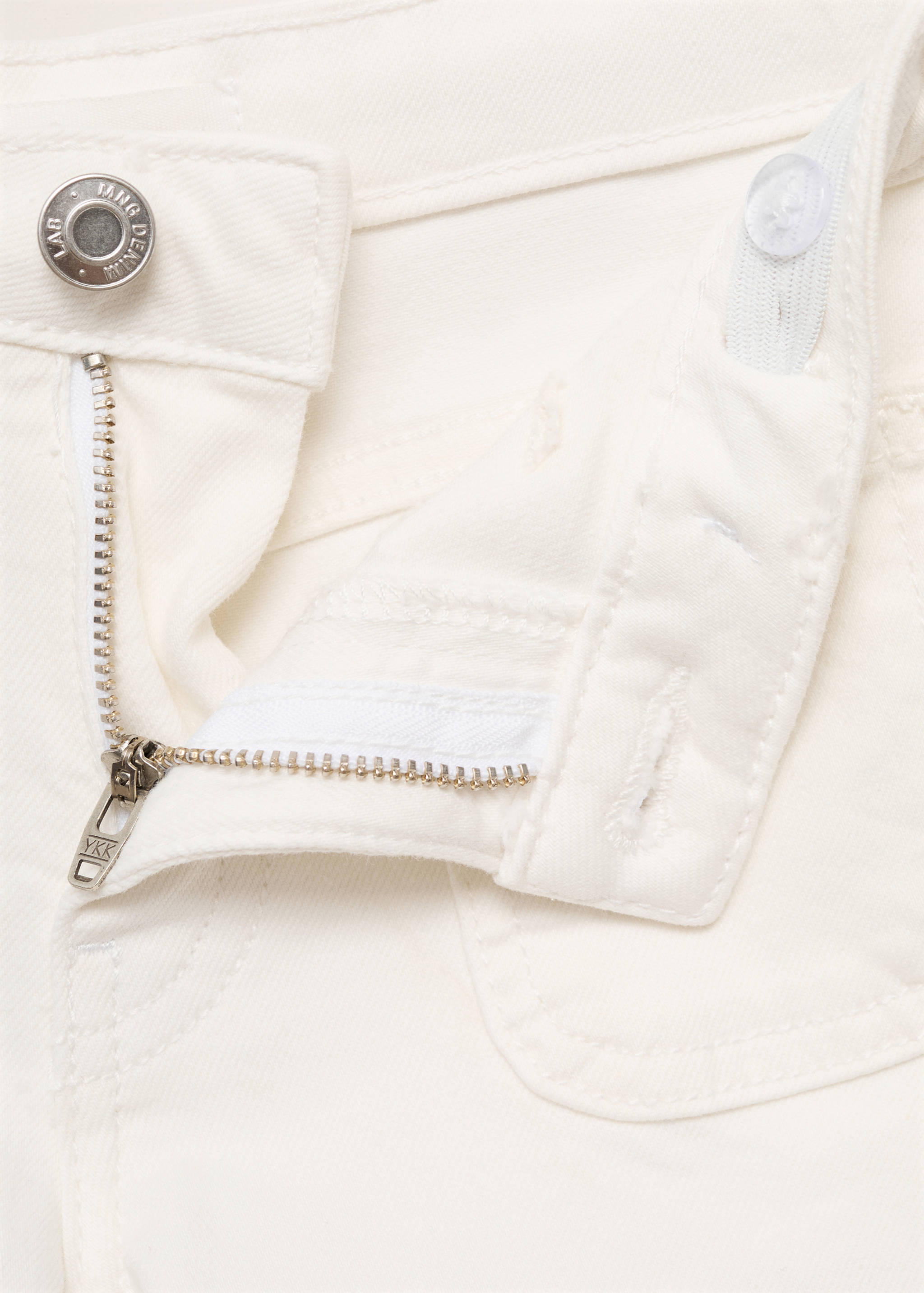 Close-up of white shorts with a metal button and zippered fly.