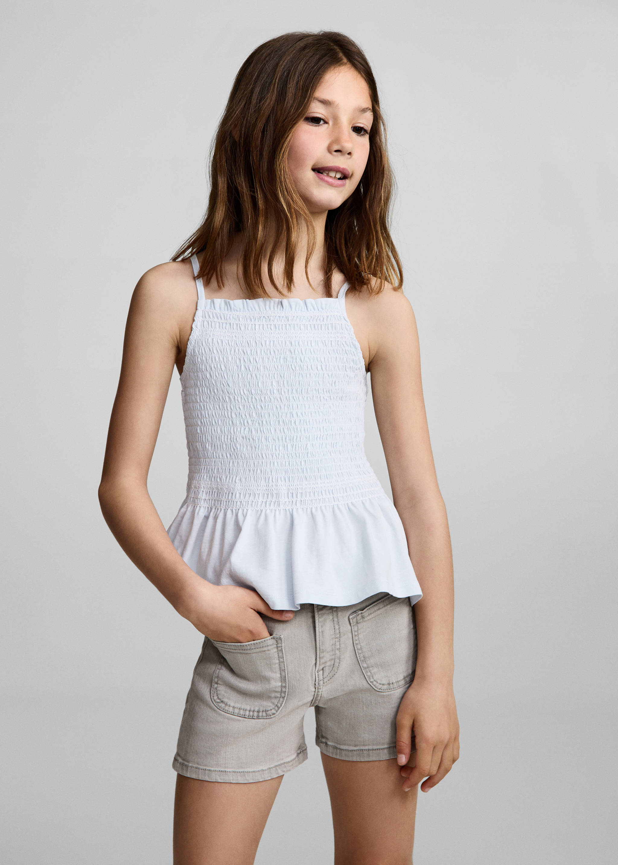 Grey denim shorts worn with a light blue smocked camisole top.