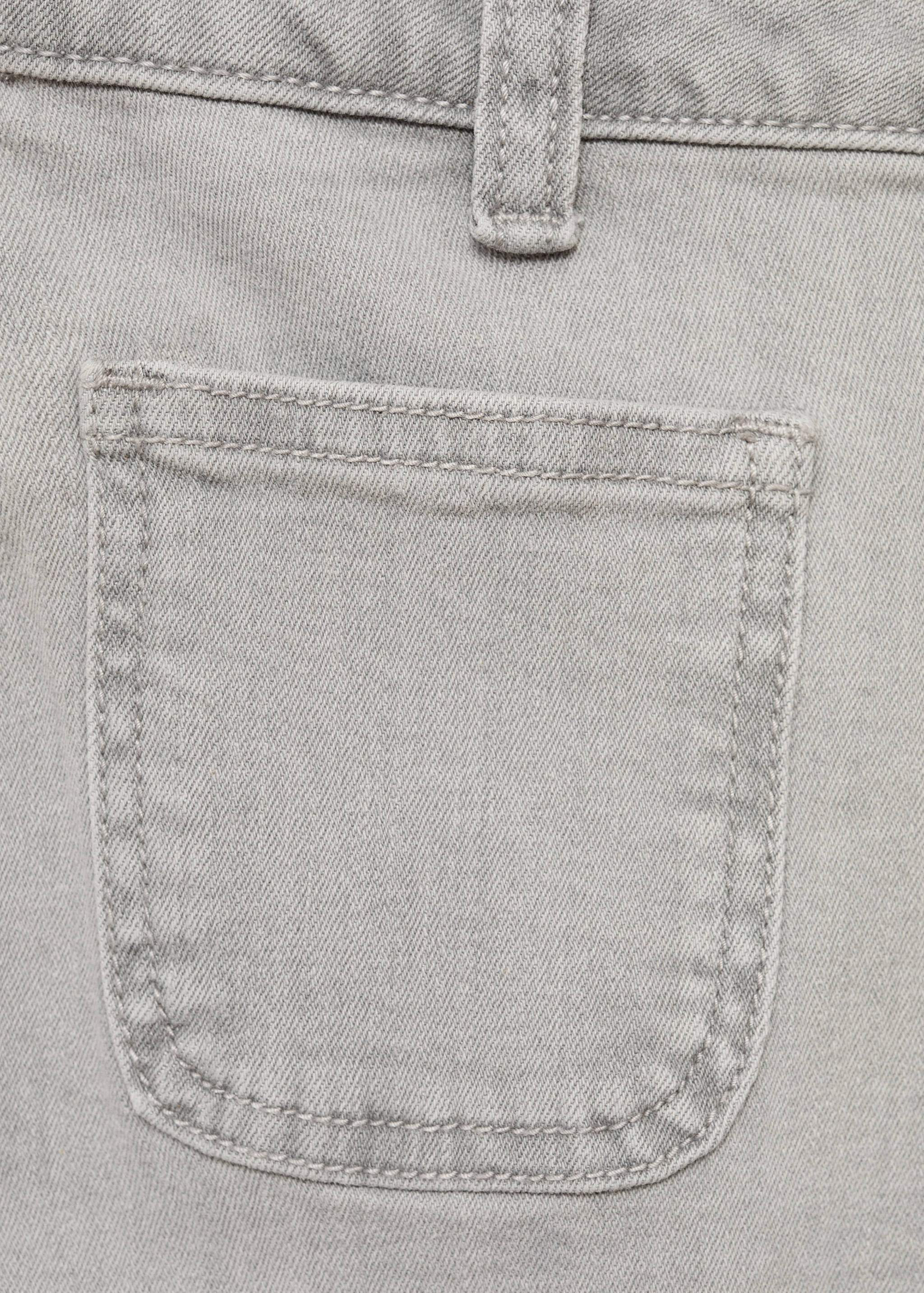 Close-up of grey denim shorts fabric showing pocket and belt loop.