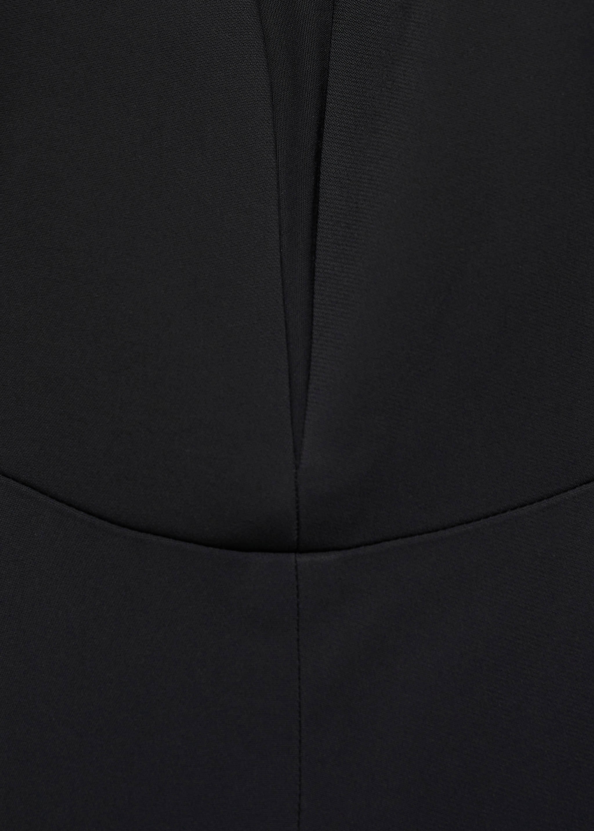 Close-up of fabric and neckline detail on a black jumpsuit.