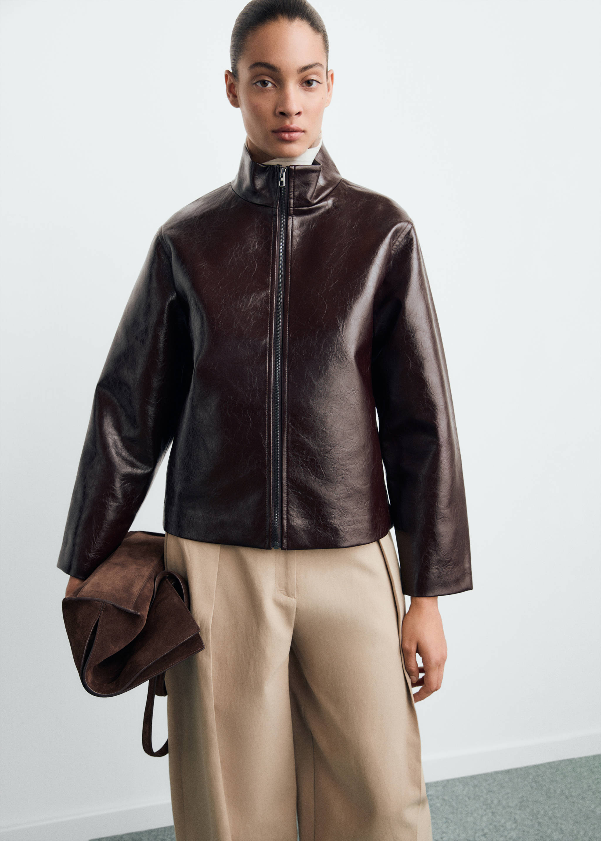 Dark brown glossy faux-leather jacket with a high collar and zip closure.