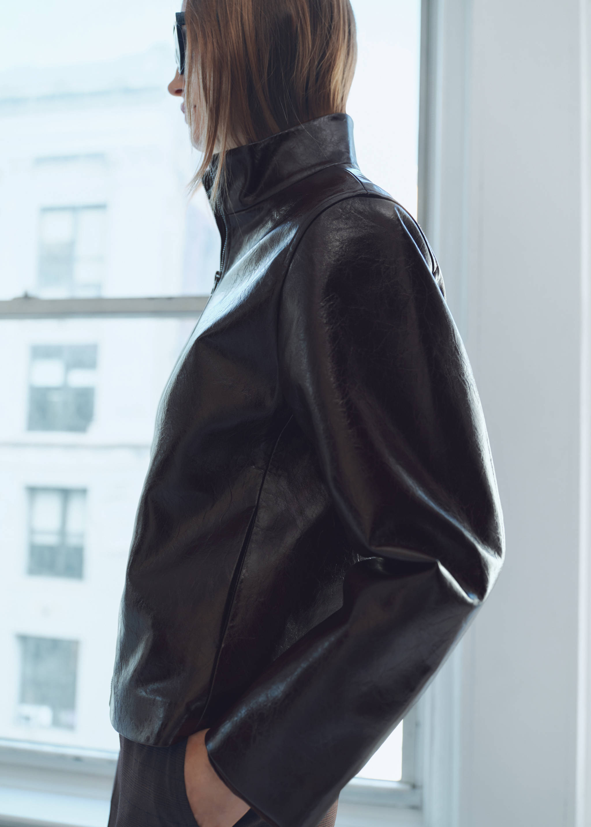 Dark brown glossy jacket with a high collar in a close-up model view.