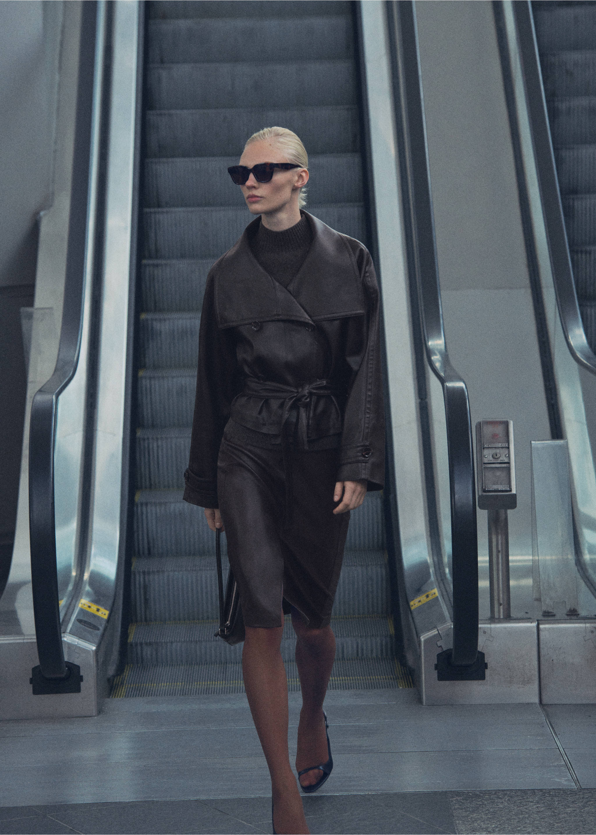 Dark brown leather jacket with an oversized collar and tie belt, worn descending an escalator., Brown. Ref: 87070651-00.