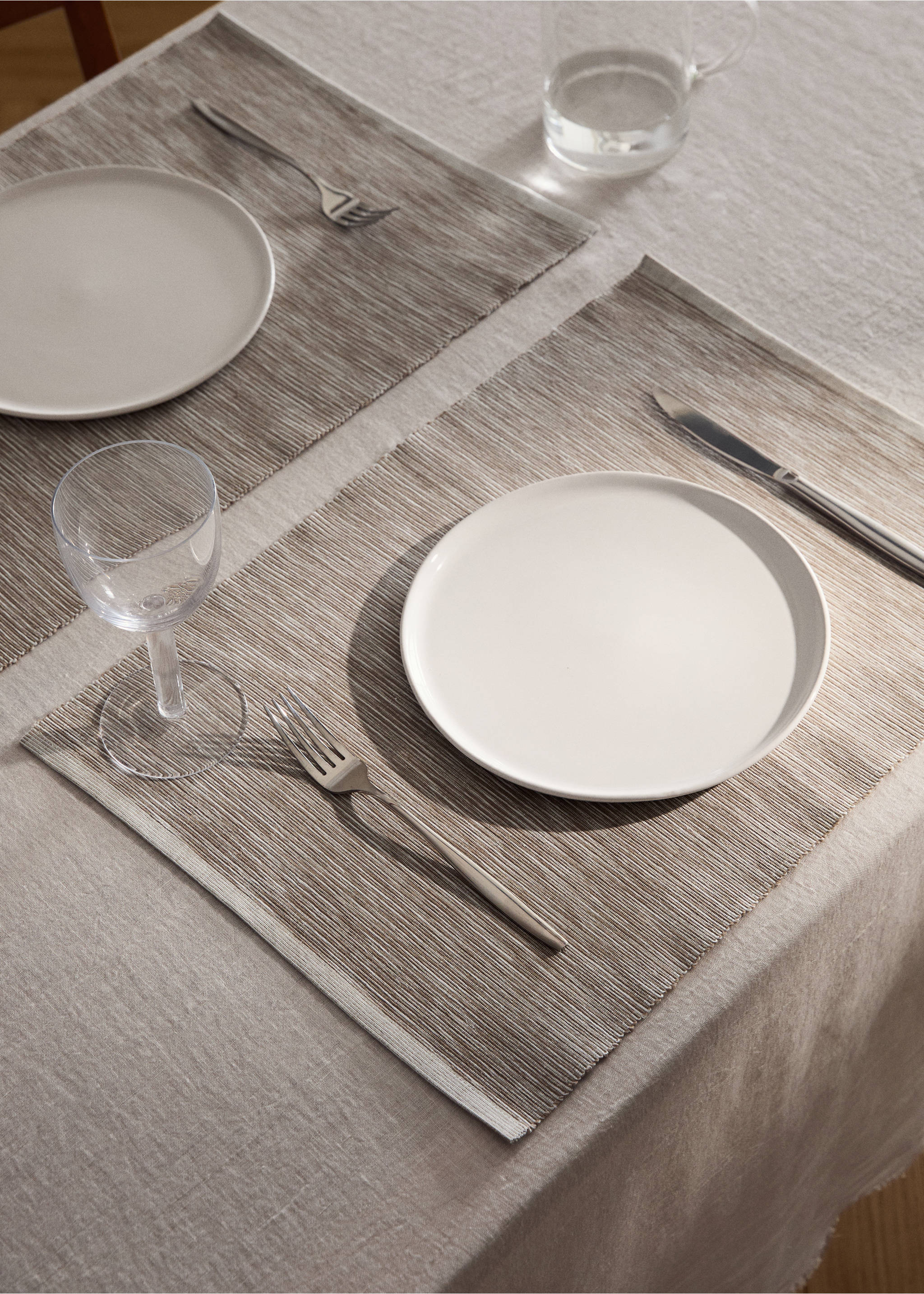 Rectangular taupe and white striped placemat set on a dining table., Sand. Ref: 87072978-00.