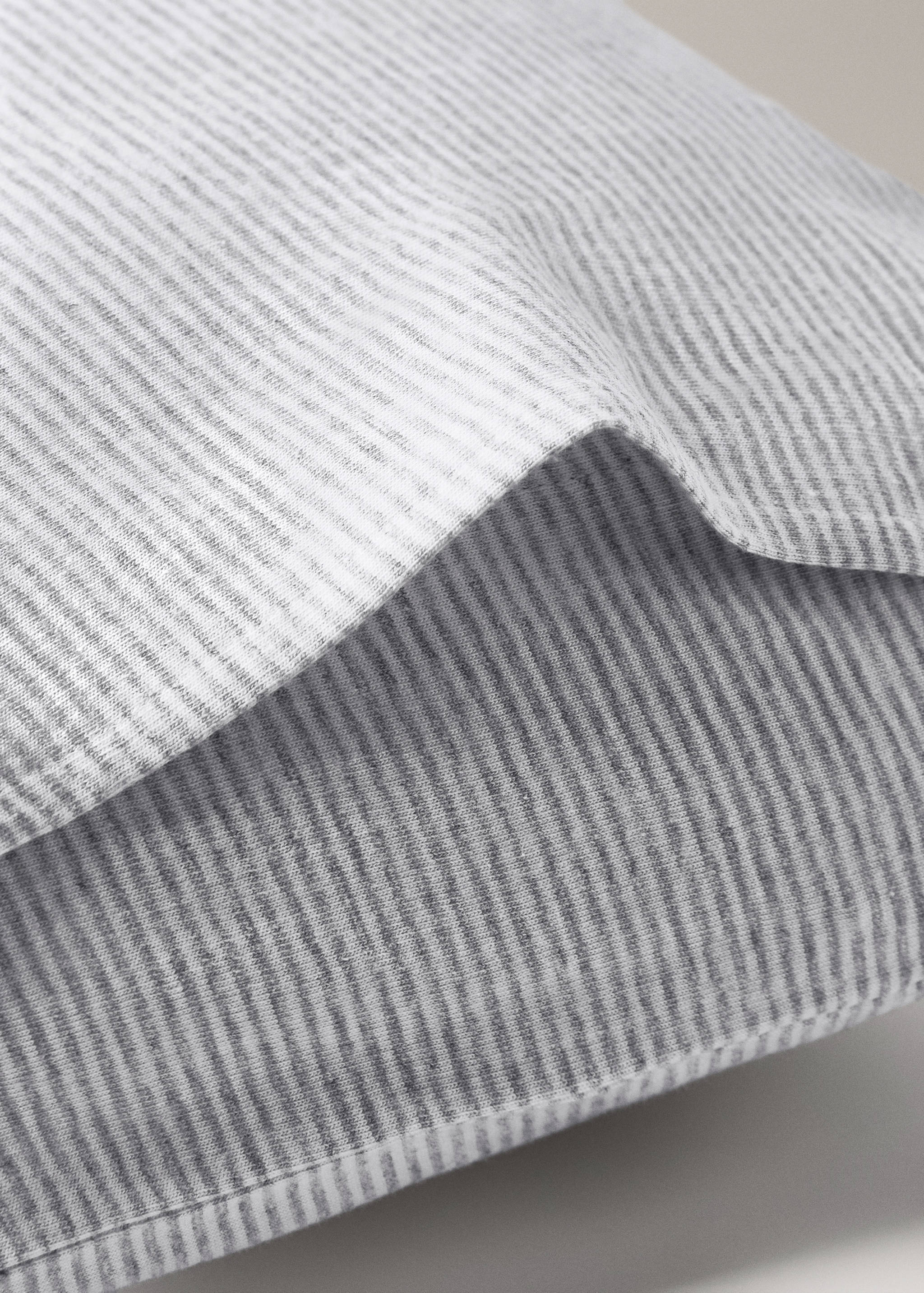 Grey and white striped cot pillowcase close-up view.