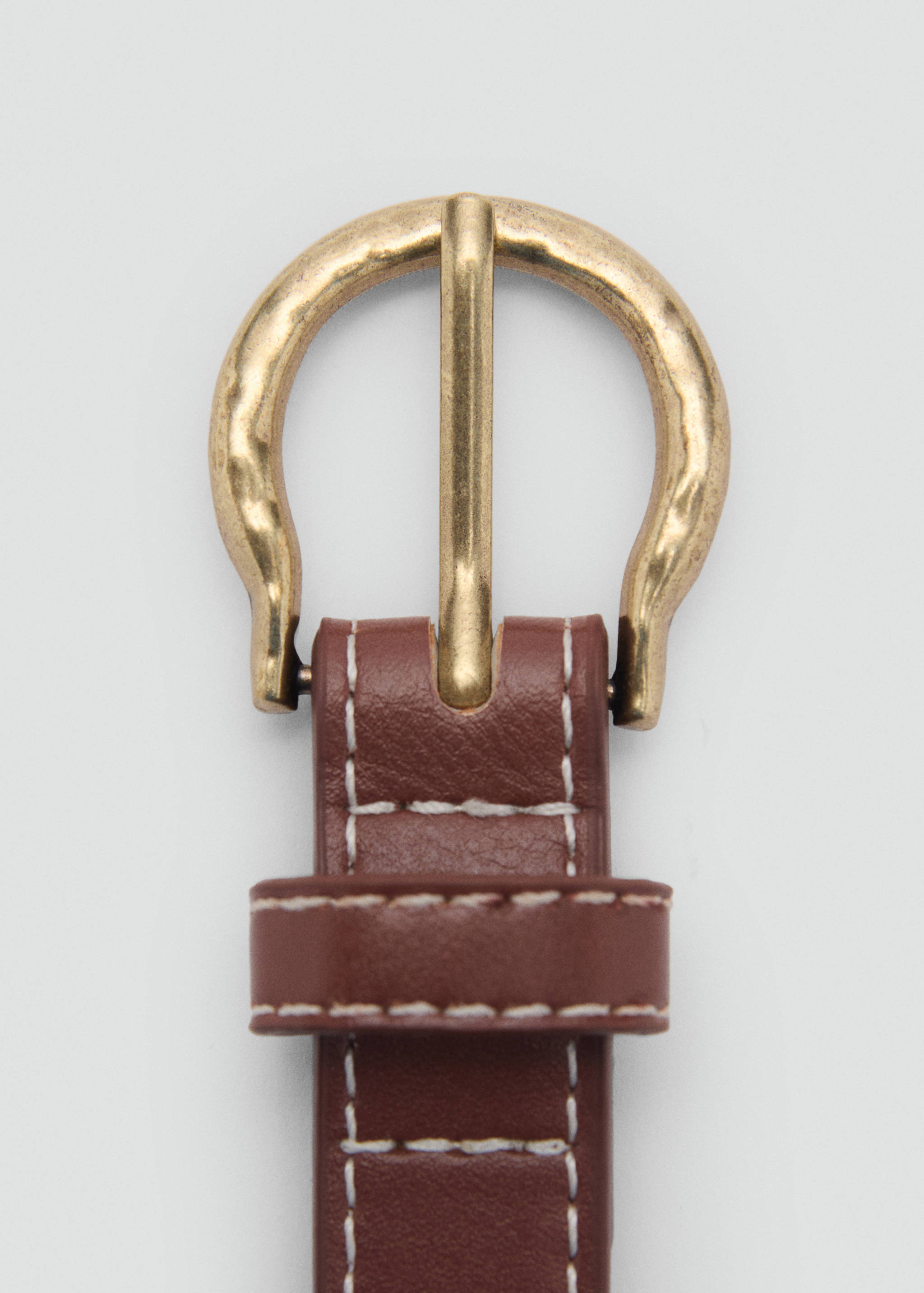 Close-up of a brown leather belt with white topstitching and a rounded brass-toned buckle.