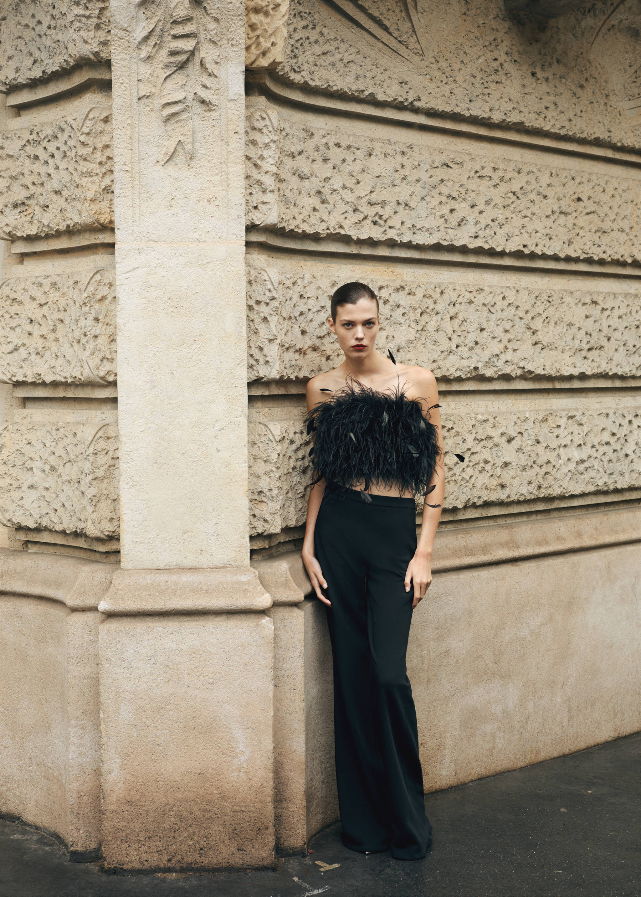 Black strapless feather top worn with black trousers.