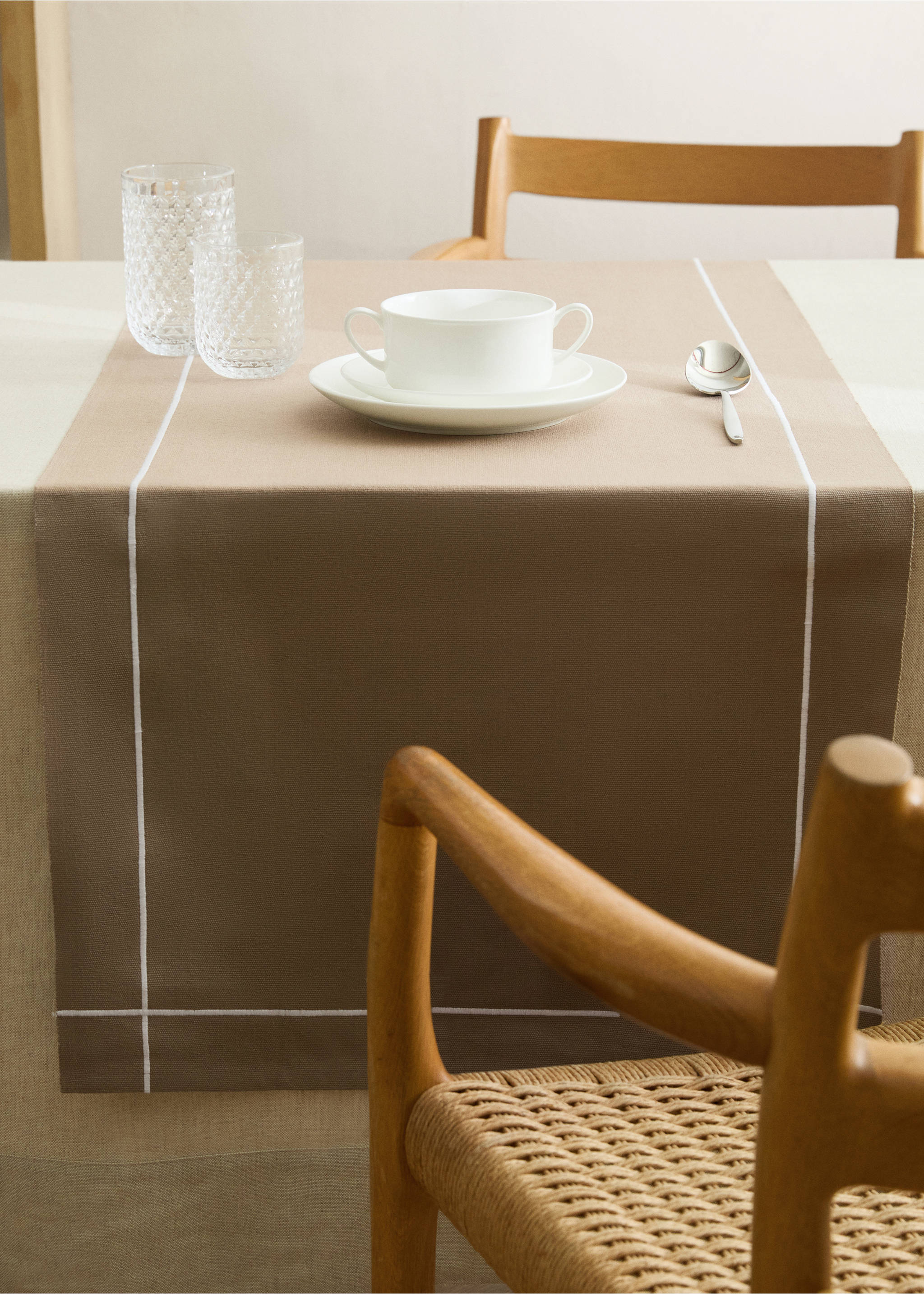Brown table runner with white embroidered lines on a table., Sand. Ref: 87082977-00.