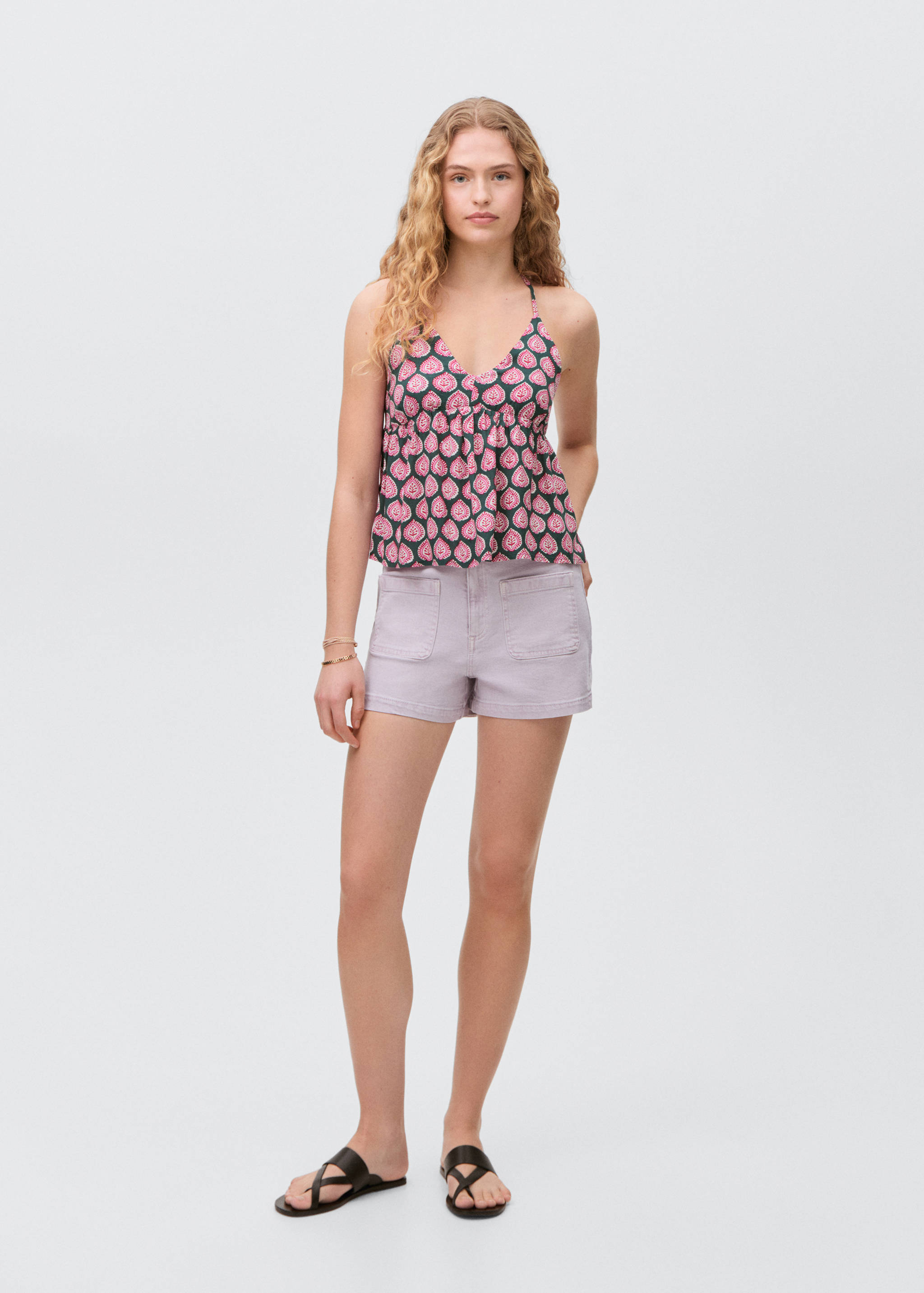 Pink and green patterned top with a V-neck and thin straps, worn with lilac shorts.