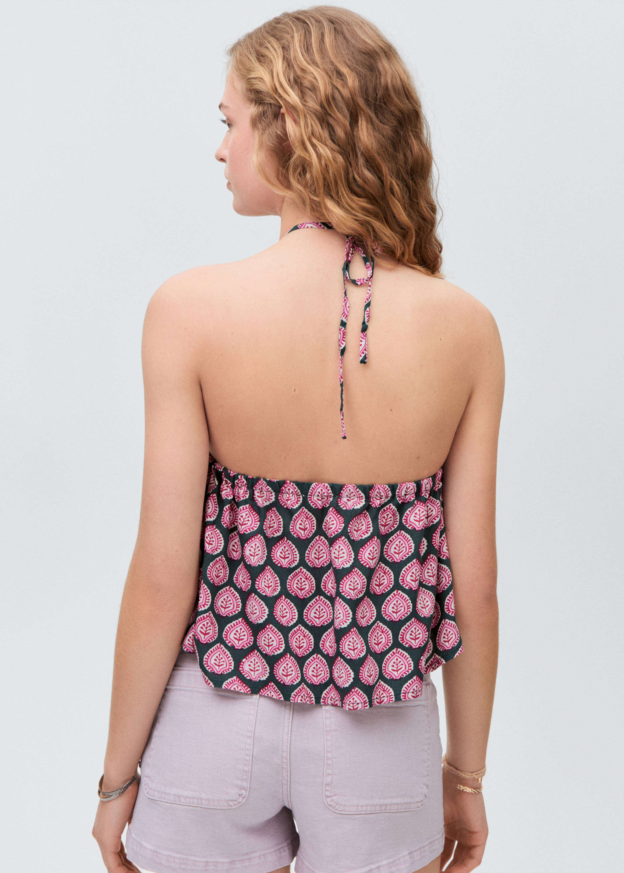 Back view of a green and pink printed halter top with a gathered back.