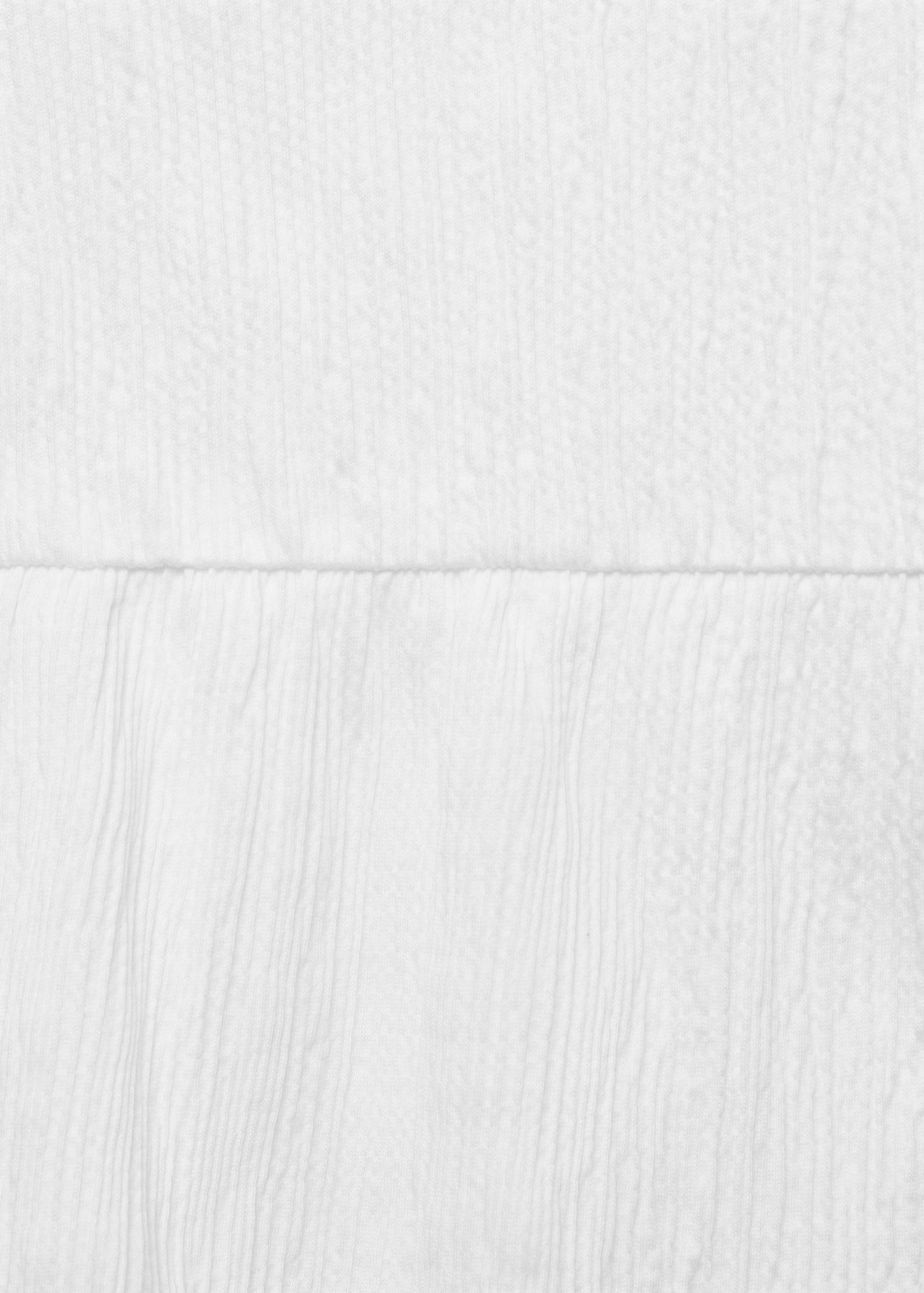 Close-up of the white textured fabric detail of a top.