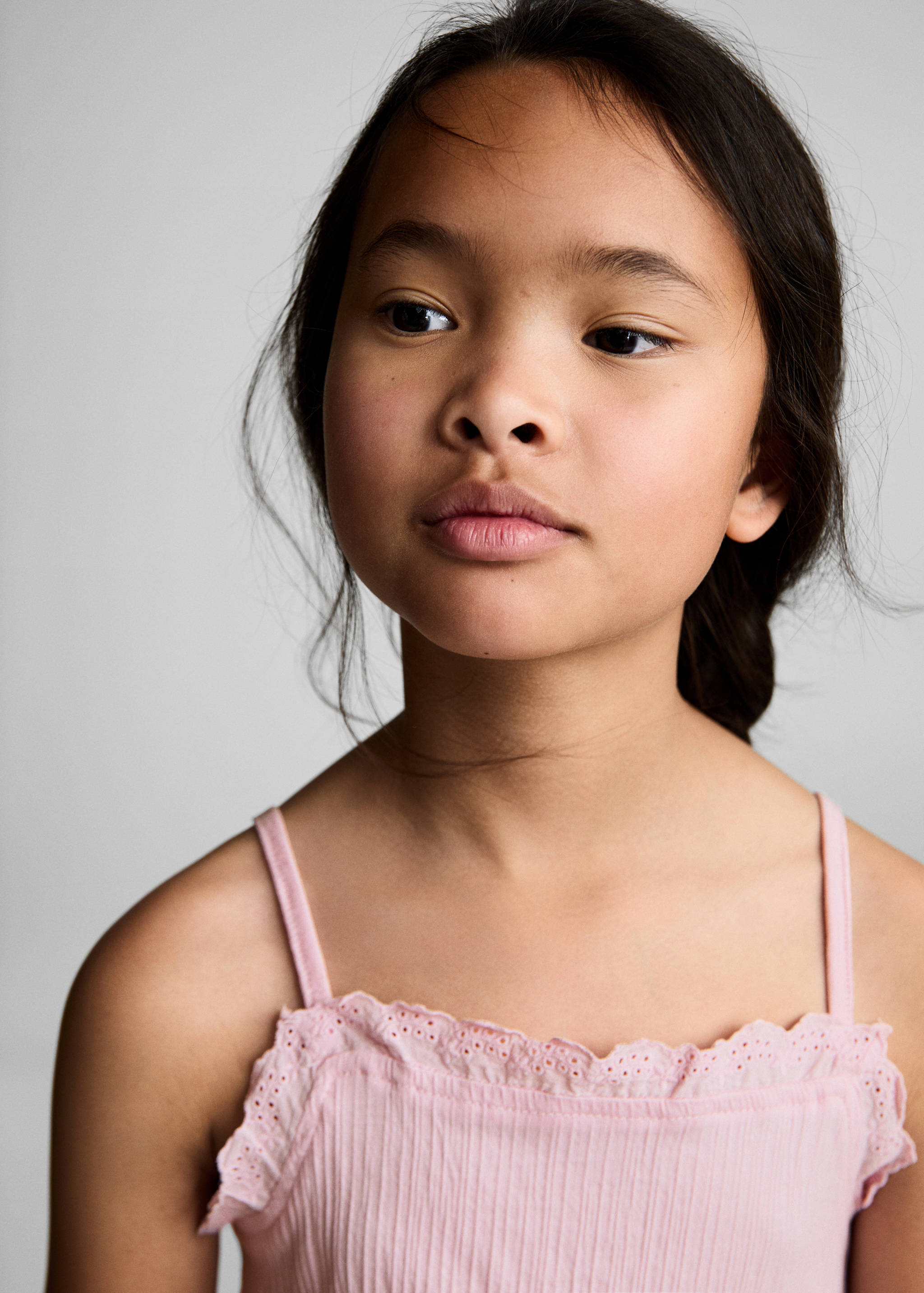 Pink top with thin straps and a scalloped eyelet trim neckline.