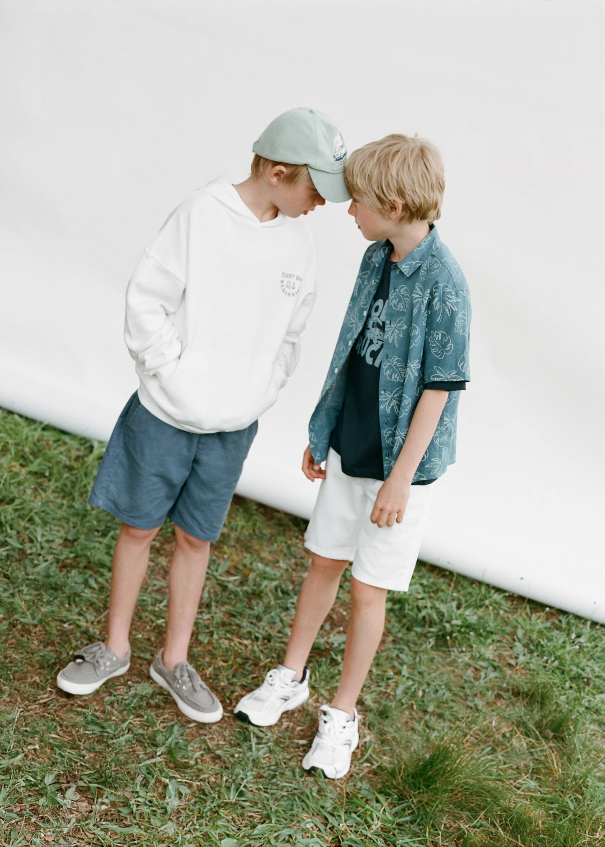 Dark grey-blue bermuda shorts worn by a boy in an off-white hoodie., White. Ref: 87097701-00.
